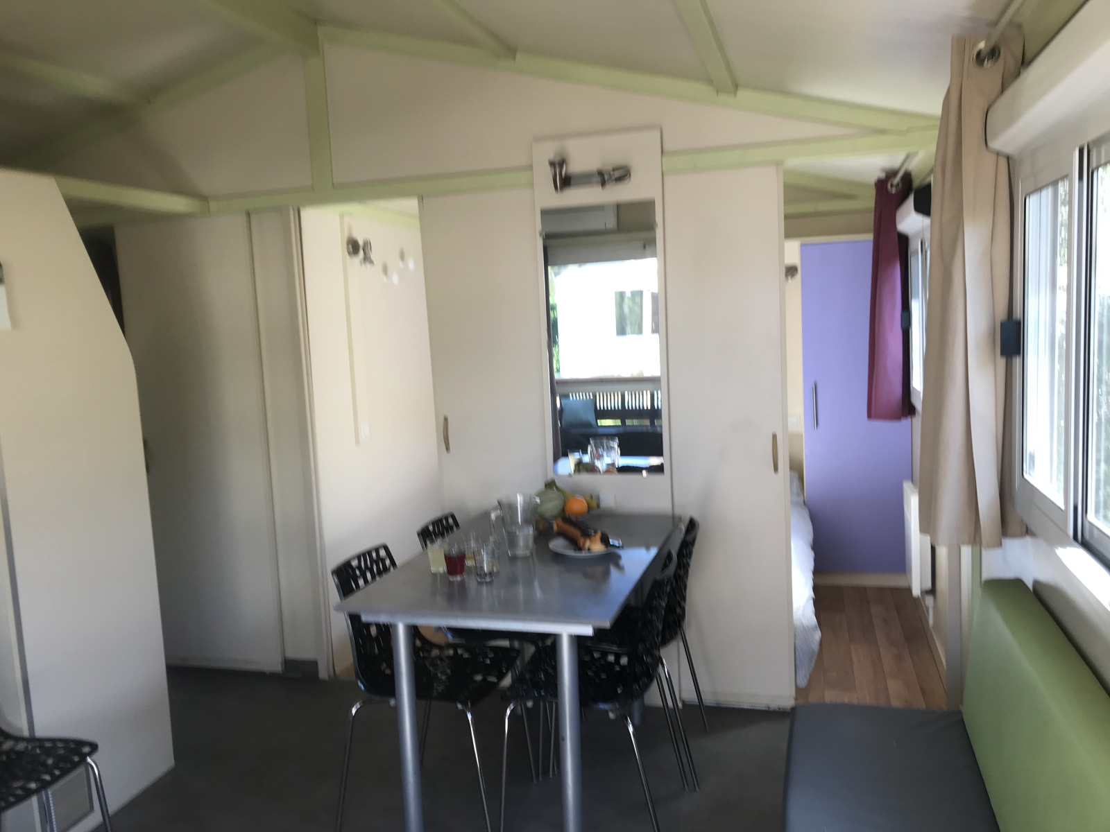 Interieur van Chalet du Bélier + Jacuzzi bij Flower Camping de la Trye, met eettafel en ramen zichtbaar.