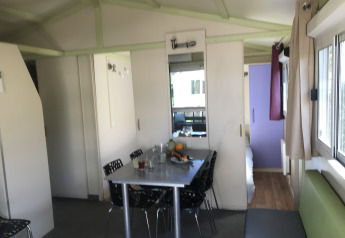 Indvendig udsigt over Chalet du Bélier + Jacuzzi på Flower Camping de la Trye, med spisebord og vinduer.