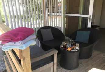 Udendørs terrasse med to kurvestole, et bord med snacks og drikke samt håndklæder på en bænk.