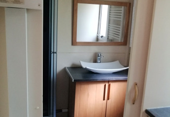 Badeværelse i Chalet du Bélier på Flower Camping de la Trye i Frankrig, med spejl, håndvask og brusebad.