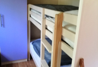 Slaapkamer met stapelbed en paarse kast in Chalet du Bélier bij Flower Camping de la Trye, Frankrijk.