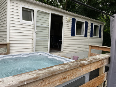 Bubbelbad buiten op houten terras bij Bungalow Les Croisettes op Flower Camping de la Trye in Frankrijk.