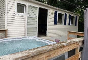 Vasca idromassaggio esterna su terrazza di legno davanti al Bungalow Les Croisettes al Flower Camping de la Trye, Francia.