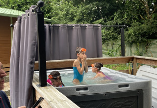 Kinderen spelen in een buitenjacuzzi bij Bungalow Les Croisettes, Flower Camping de la Trye, Frankrijk.