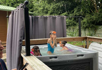 Bambini che giocano in una jacuzzi all'aperto al Bungalow Les Croisettes, Flower Camping de la Trye, Francia.