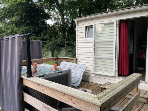 Kinderen genieten in een jacuzzi naast een bungalow met houten terras bij Flower Camping de la Trye in Frankrijk.