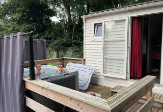Kinderen genieten in een jacuzzi naast een bungalow met houten terras bij Flower Camping de la Trye in Frankrijk.