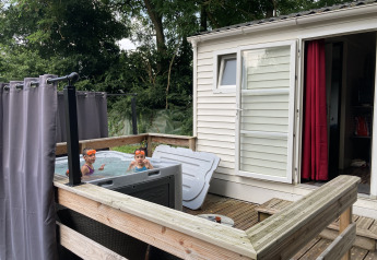 Bambini che si divertono in una jacuzzi all’aperto accanto a un bungalow al Flower Camping de la Trye, Francia.