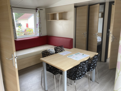 Interni della Mobile home «Grand Confort» al Flower Camping de la Trye, Francia, con tavolo e divano ad angolo.