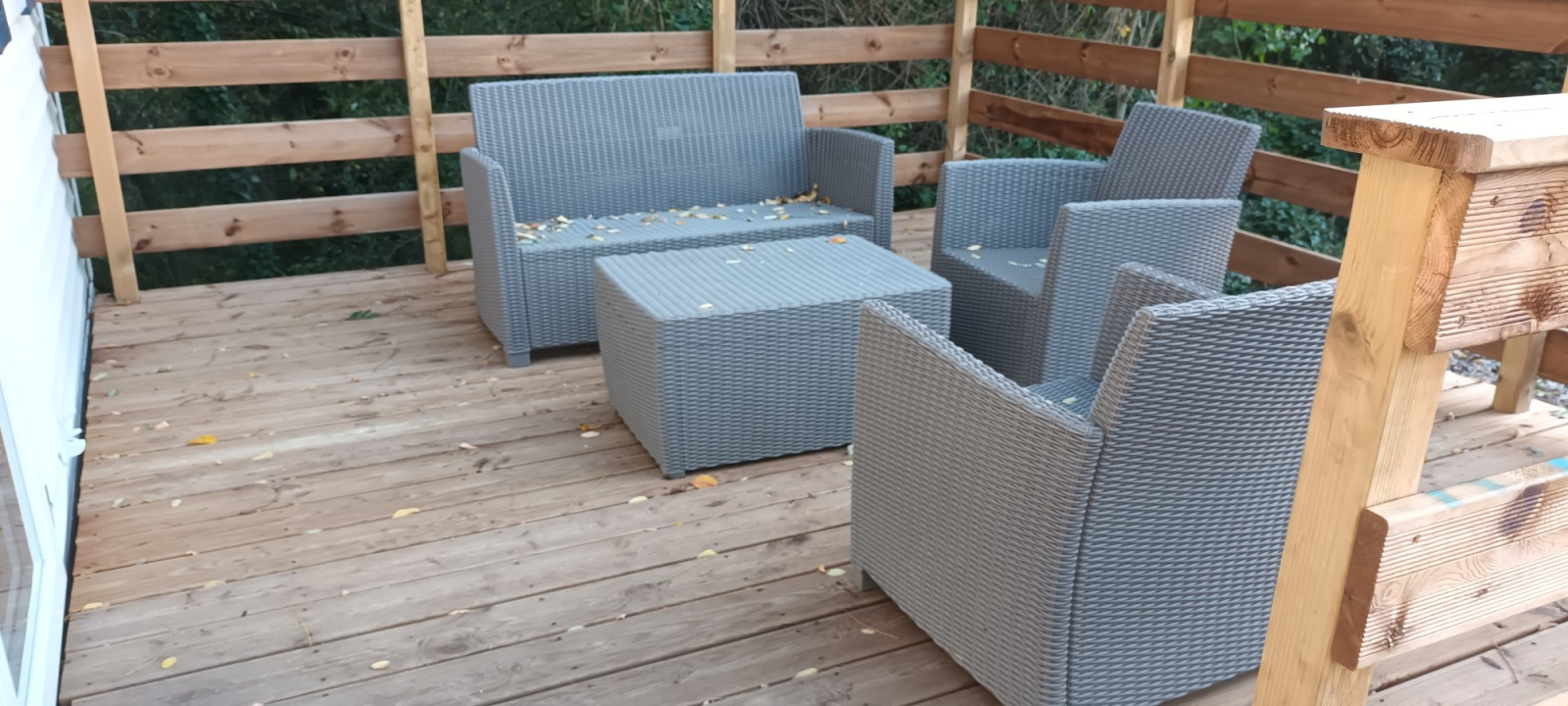 Houten terras met grijze rotan meubels bij Mobile home 'Grand Confort', Flower Camping de la Trye in Frankrijk.