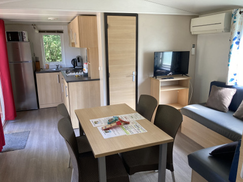 Binnenzicht van Bungalow du Parc + jacuzzi aan Flower Camping de la Trye, Frankrijk, met keuken en zithoek.