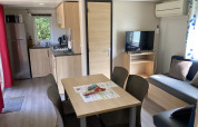 Interieur van Bungalow du Parc + jacuzzi bij Flower Camping de la Trye, Frankrijk, met keuken en zithoek.