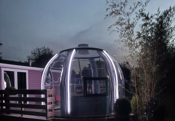 Tente glamping dôme avec jacuzzi et lumières LED au Flower Camping de la Trye en France au crépuscule.