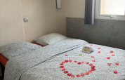 Een knusse lodge slaapkamer met rozenblaadjes en een kaart op het bed, naast een raam met licht.