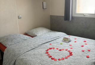 Gezellige lodge slaapkamer met rozenblaadjes in hartvorm en een kaartje op het bed naast het raam.