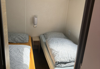 Kleine kamer met twee enkele bedden en een nachtkastje in Bungalow La Folle Entreprise bij Flower Camping de la Trye.