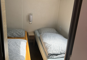 Petite chambre avec deux lits simples et une table de chevet au Bungalow La Folle Entreprise à Flower Camping de la Trye.
