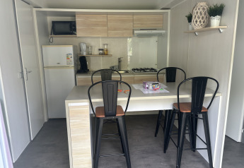 Compact lodge kitchen with dining table, four high chairs, and modern appliances, including a gas stove.