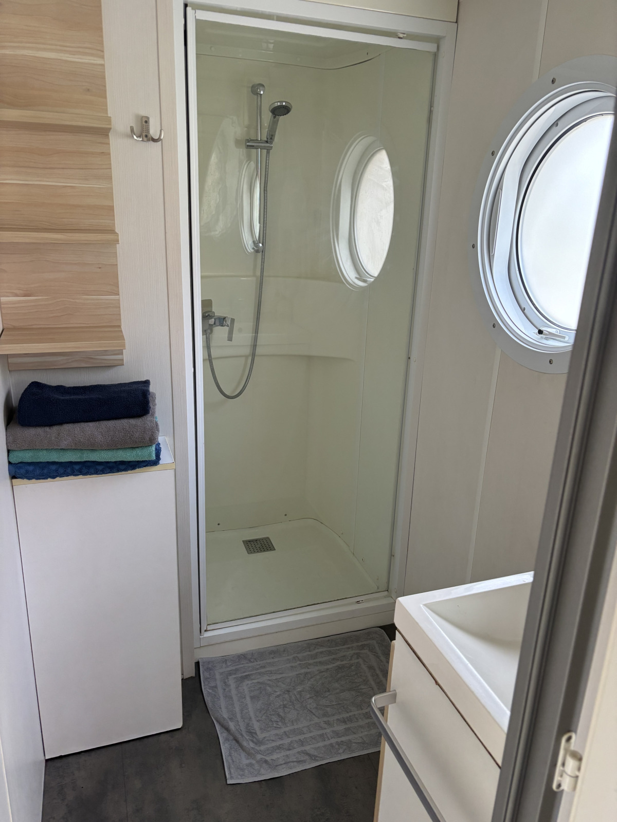 Moderne lodgebadkamer met glazen douche, ronde patrijspoort, handdoeken en wastafel