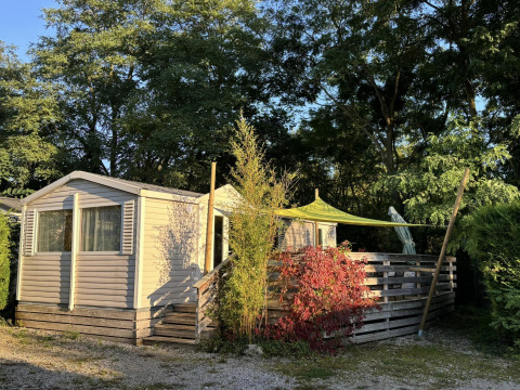 Bungalow du Gorguet met jacuzzi bij Flower Camping de la Trye in Frankrijk, omgeven door bomen en zon.