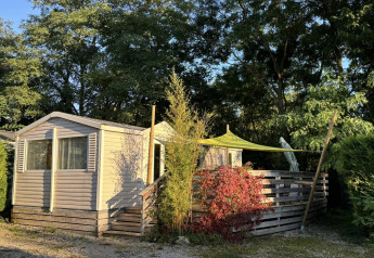 Bungalow du Gorguet with jacuzzi at Flower Camping de la Trye in France, surrounded by trees, in sunlight.