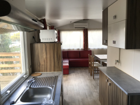 Moderne keuken en leefruimte van Bungalow du Gorguet met sofa en eettafel bij Flower Camping de la Trye.