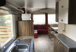 Moderne keuken en leefruimte van Bungalow du Gorguet met sofa en eettafel bij Flower Camping de la Trye.