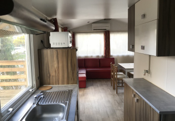 Modern kitchen and living space in Bungalow du Gorguet, featuring sofa and dining area at Flower Camping de la Trye.