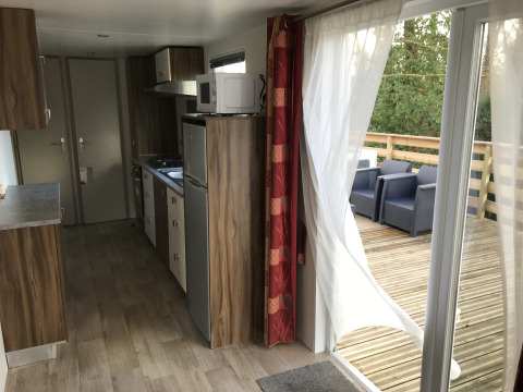 Modern chaletinterieur met keuken en toegang tot houten terras met zitplaats op een Franse camping.
