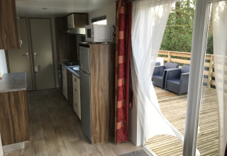 Modern chaletinterieur met keuken en toegang tot houten terras met zitplaats op een Franse camping.
