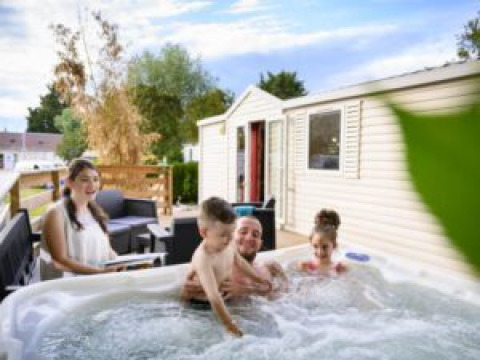Gezin geniet van jacuzzi bij hun lodge aan Bungalow du Gorguet, Flower Camping de la Trye, Frankrijk.