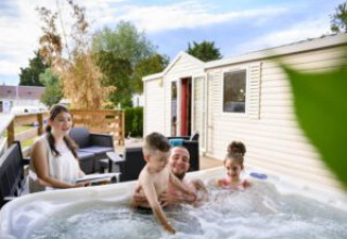 Gezin geniet van jacuzzi bij hun lodge aan Bungalow du Gorguet, Flower Camping de la Trye, Frankrijk.