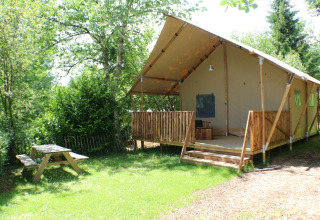 Safari Lodge tent at Campsite Moulin de Chaules, France, featuring a wooden deck and picnic table in nature.