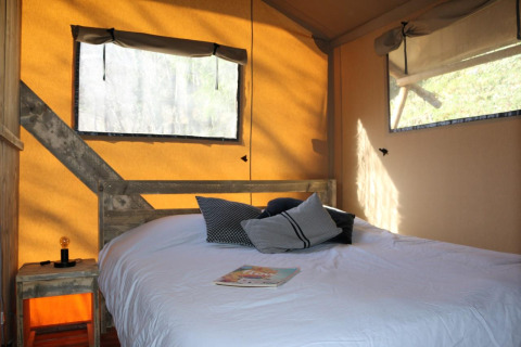 Interno della tenda Safari Lodge al campeggio Moulin de Chaules in Francia, con letto e finestre.