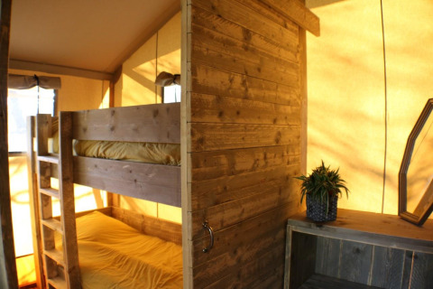 Interieur van de Safari Lodge tent op Camping Moulin de Chaules met stapelbed en houten inrichting.
