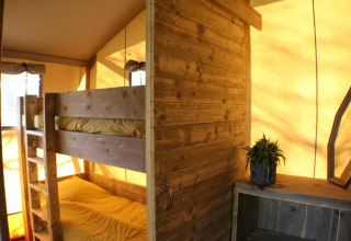 Interno della tenda Safari Lodge al campeggio Moulin de Chaules, Francia, con letti a castello e arredi in legno.