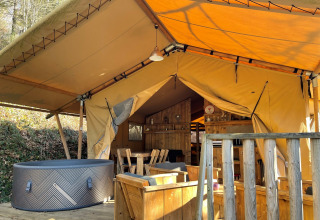 Safari Lodge tent at Campsite Moulin de Chaules in France, showing a wooden deck, seating, and hot tub.