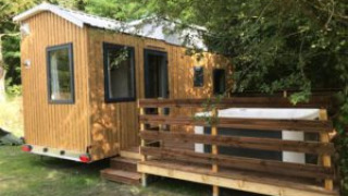 Foto di una Tiny House chiamata Tiny House + jacuzzi, con terrazza in legno e circondata dagli alberi.