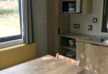 Interior view of a tiny tree house with dining table, chairs, and kitchenette at Flower Camping de la Trye.