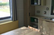Interieur van een tiny house met eettafel, stoelen en kitchenette bij Flower Camping de la Trye.