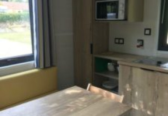 Vue intérieure d’une tiny house avec table à manger, chaises et coin cuisine au Flower Camping de la Trye.