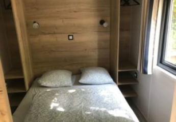 Chambre dans une Tiny House avec lit double et murs en bois, Flower Camping de la Trye, France.
