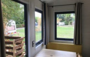 Uitzicht vanuit een Tiny House met grote ramen bij Flower Camping de la Trye in Frankrijk.