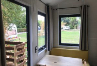 Uitzicht vanuit een Tiny House met grote ramen bij Flower Camping de la Trye in Frankrijk.