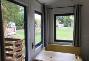 Vue intérieure d'une Tiny House aux grandes fenêtres au Flower Camping de la Trye, en France.
