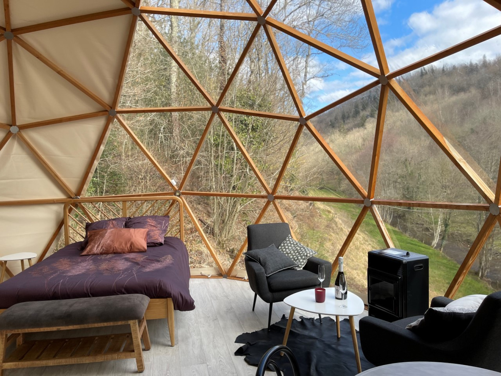 Interieur van de Dôme Lodge op camping Moulin de Chaules in Frankrijk met bed en prachtig buitenzicht.