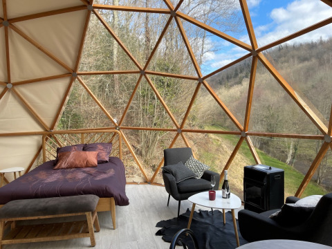 Interno della Dôme Lodge al campeggio Moulin de Chaules in Francia con letto, sedie e vista panoramica.