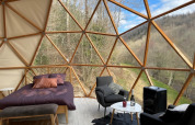 Interno della Dôme Lodge al campeggio Moulin de Chaules in Francia con letto, sedie e vista panoramica.