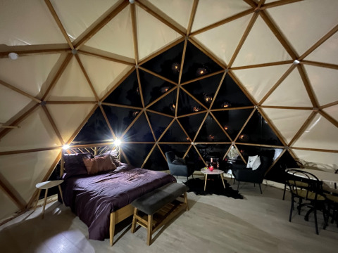 Interior view of a cozy Dôme Lodge at Campsite Moulin de Chaules, featuring a bed and comfortable seating.