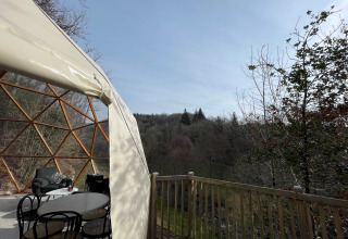 Vista desde Dôme Lodge en el Camping Moulin de Chaules, con cúpula, terraza y paisaje boscoso natural.